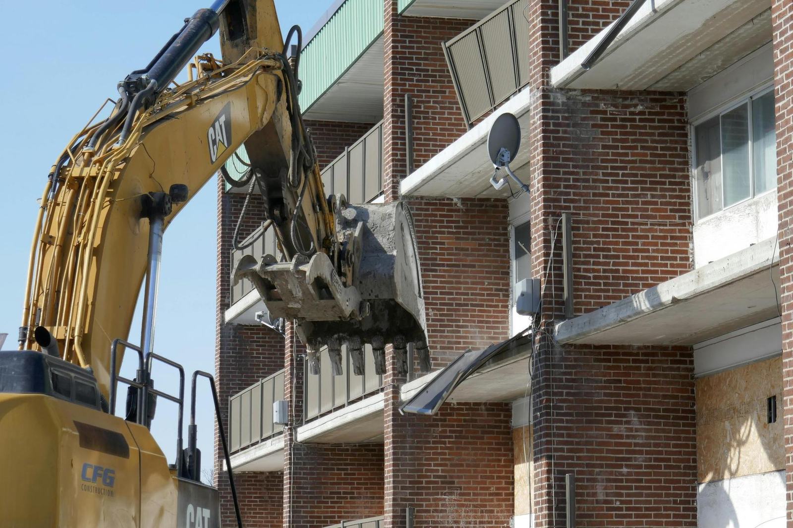 Excavator performing structural demolition on a multi-story building