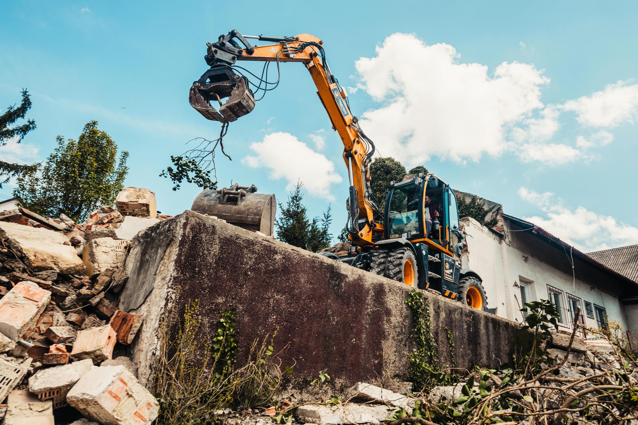 Excavator grapple handling brick debris on a Metro Detroit commercial demolition site